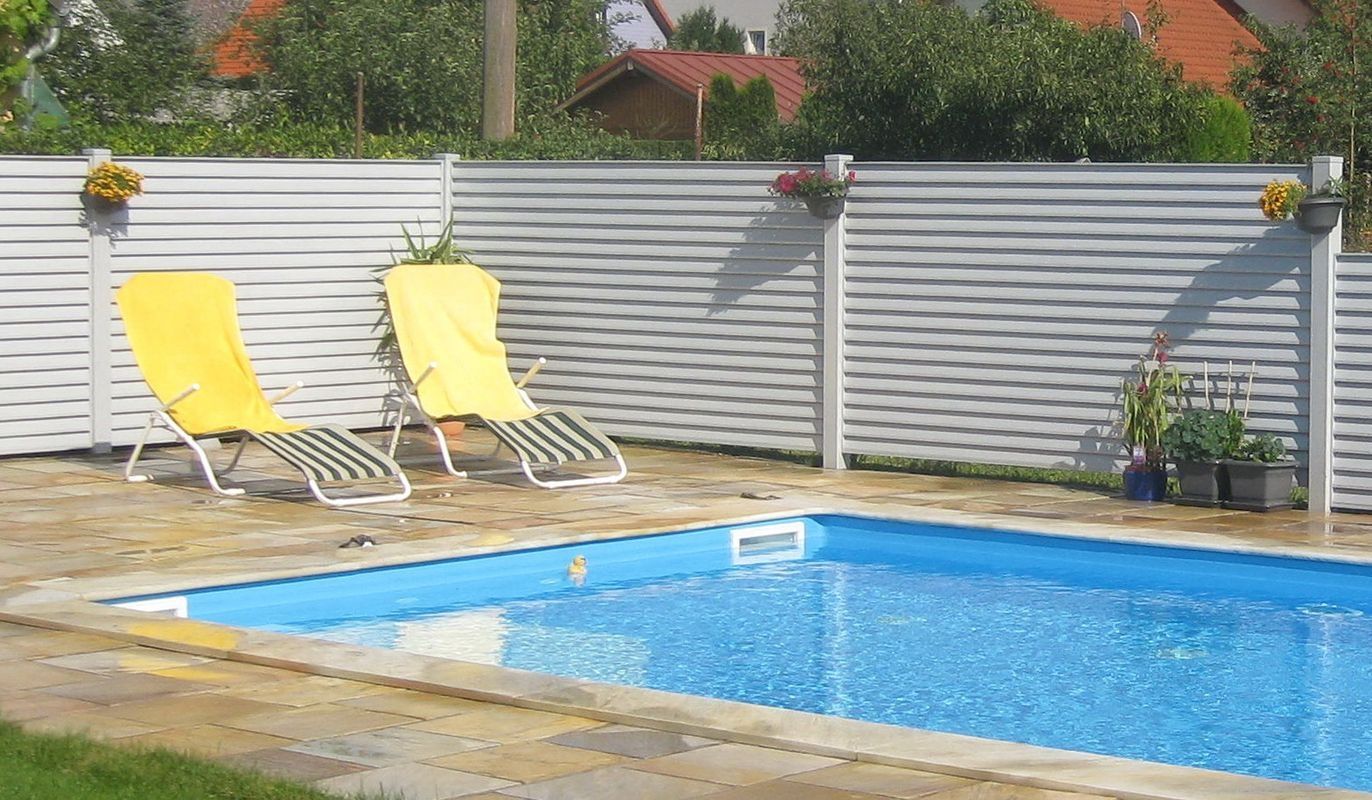 Lamellenzaun bei einem Pool mit gelben Stühlen